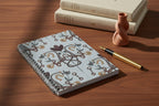 Notebook with decorative cover featuring floral and horsebit pattern on a white background