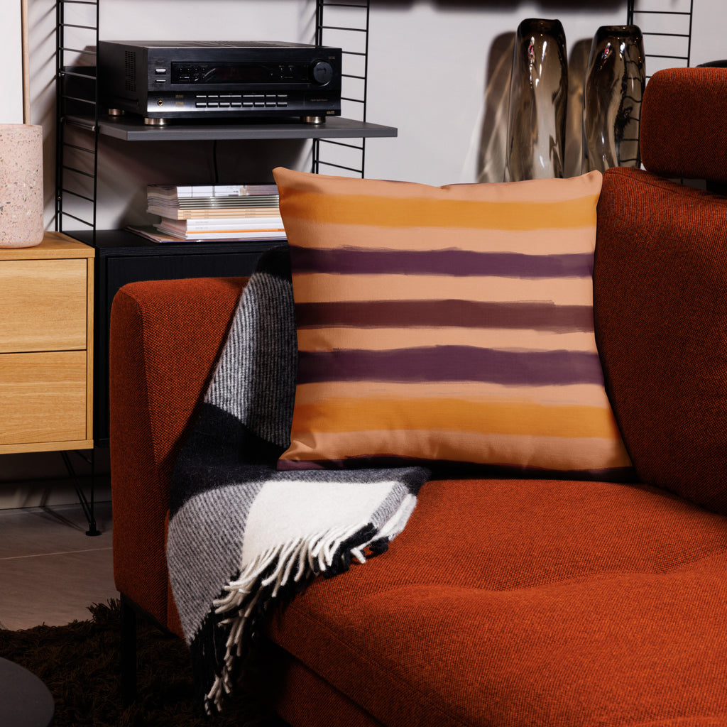 Modern living room with orange sofa, striped designer pillow, and patterned throw. Home decor accents by Design by Lola.